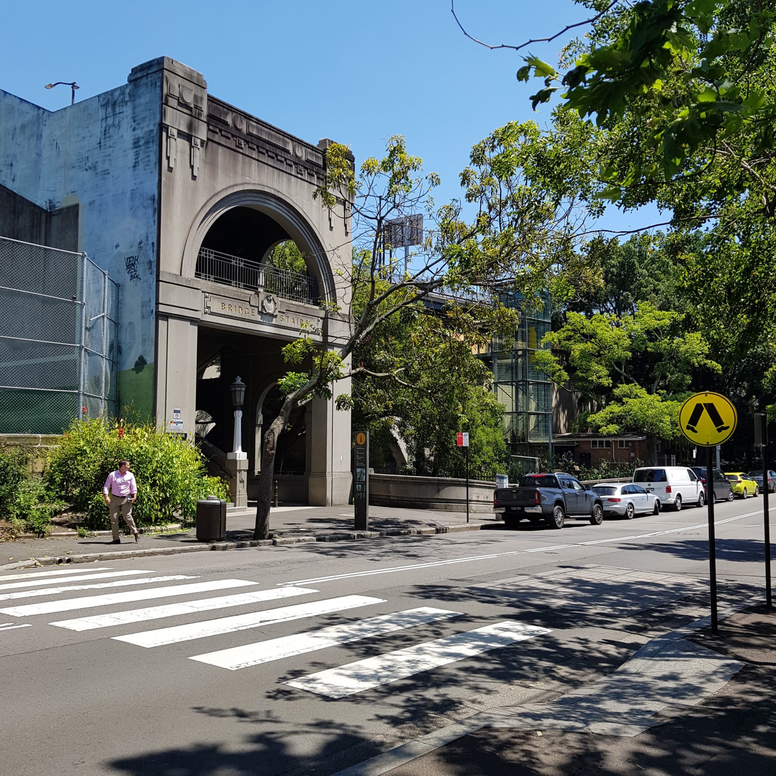 Cumberland Street, at The Rocks, with a pedestrian crossing leading to the Bridge Stairs, and vehicles parked above the Argyle Cut