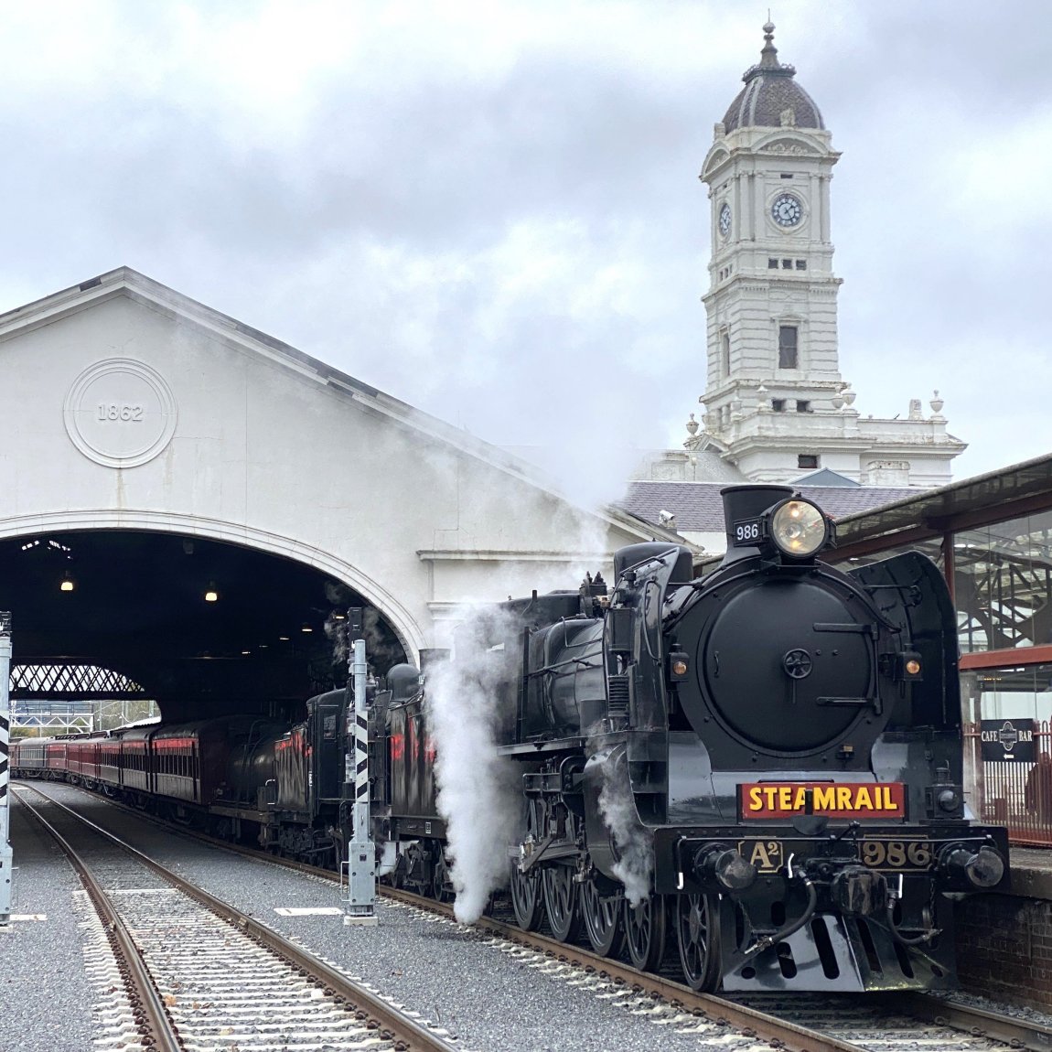 And image of Steamrail A2 986 stopped outside the Great Train Hall at Ballarat, with the Station Clock Tower prominent in the background