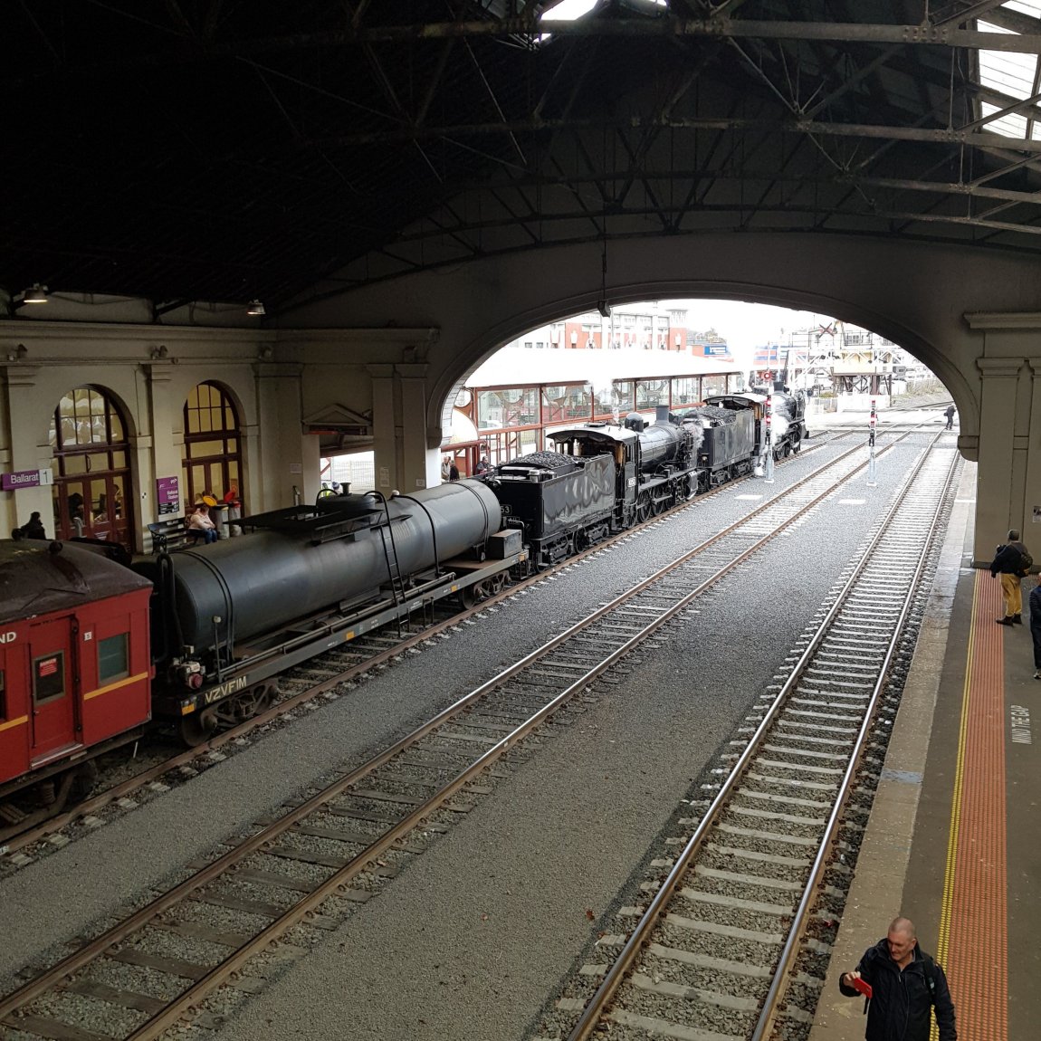 An image from the overhead bridge of the Steamrail Steam engines outside of the Great Train Hall, with Water Tank Wagon VZVF1 coupled behing them