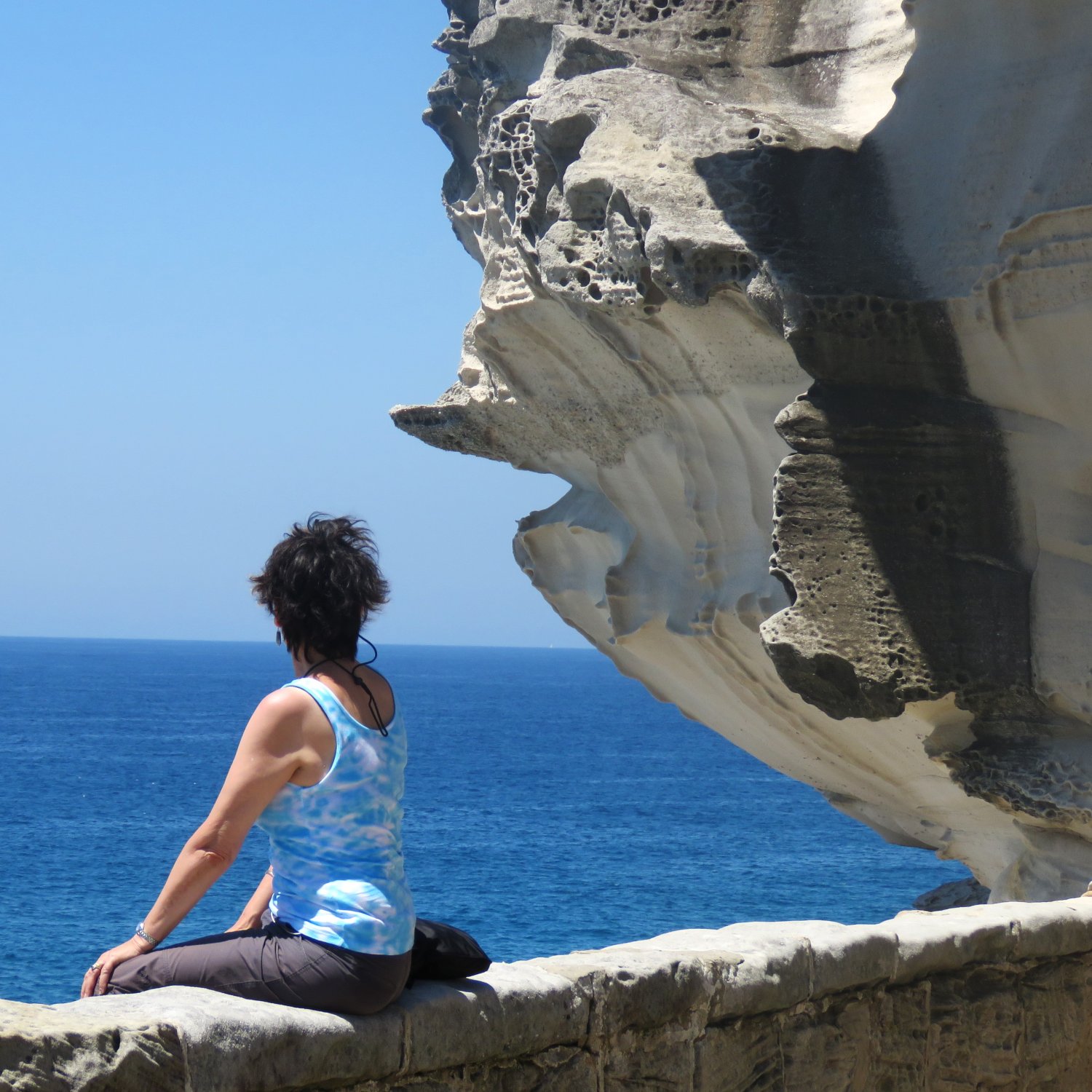 image of Marlene sitting on a seawall, looking out to sea