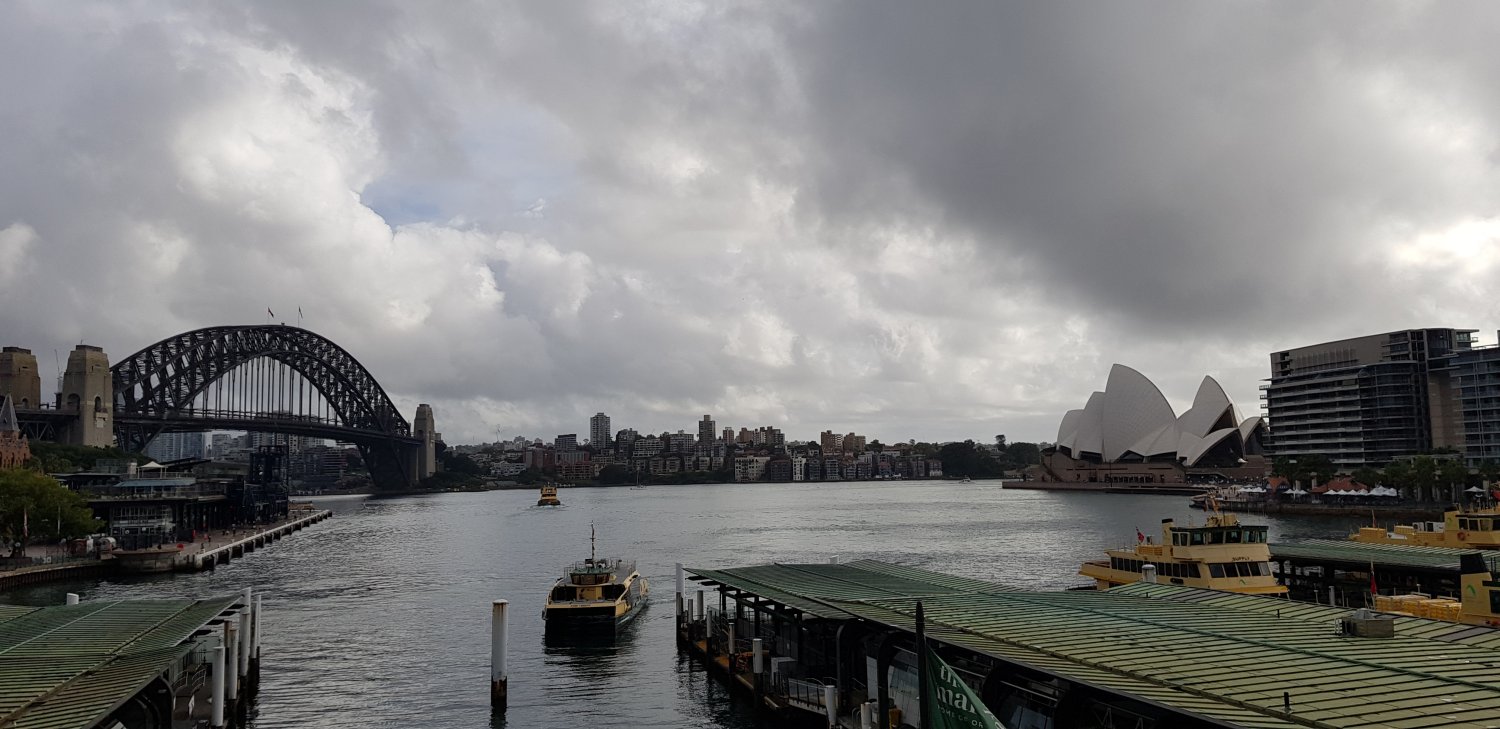 image showing a view across Circular Quay as storm clouds gather in the sky above the Harbour Bridge and the Opera House
